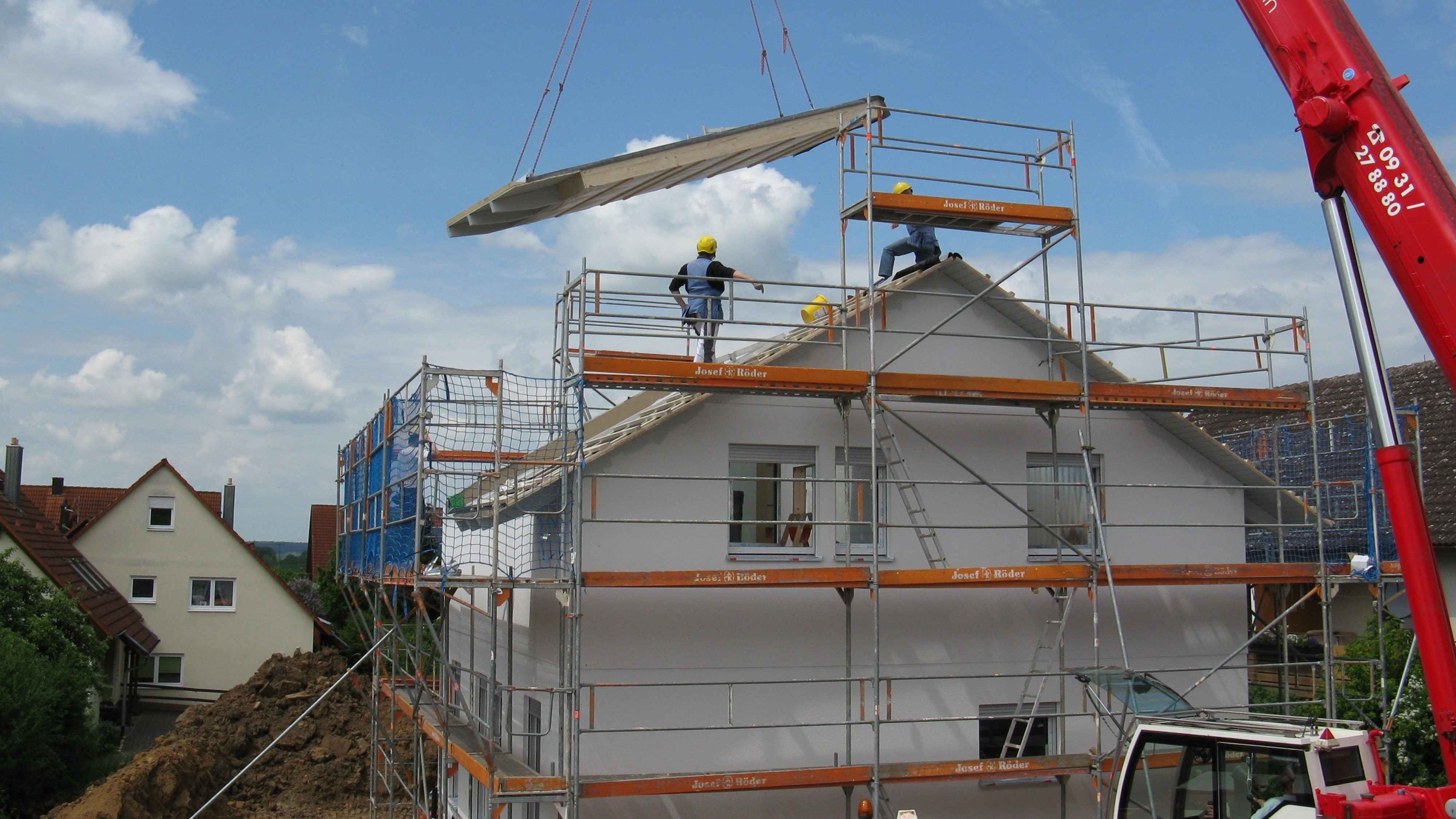 Un chantier de construction d'une maison avec un échafaudage et une grue