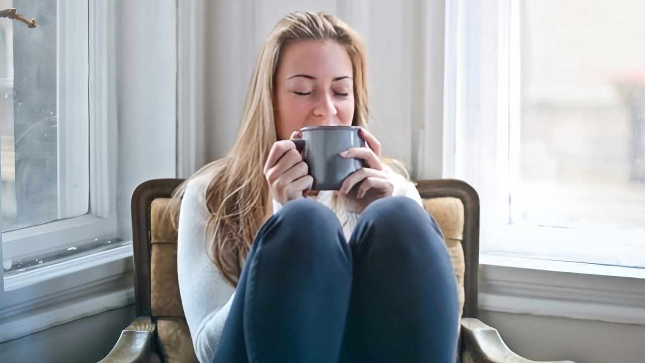Une femme se réchauffe en buvant une boisson chaude en hiver sur un fauteuil