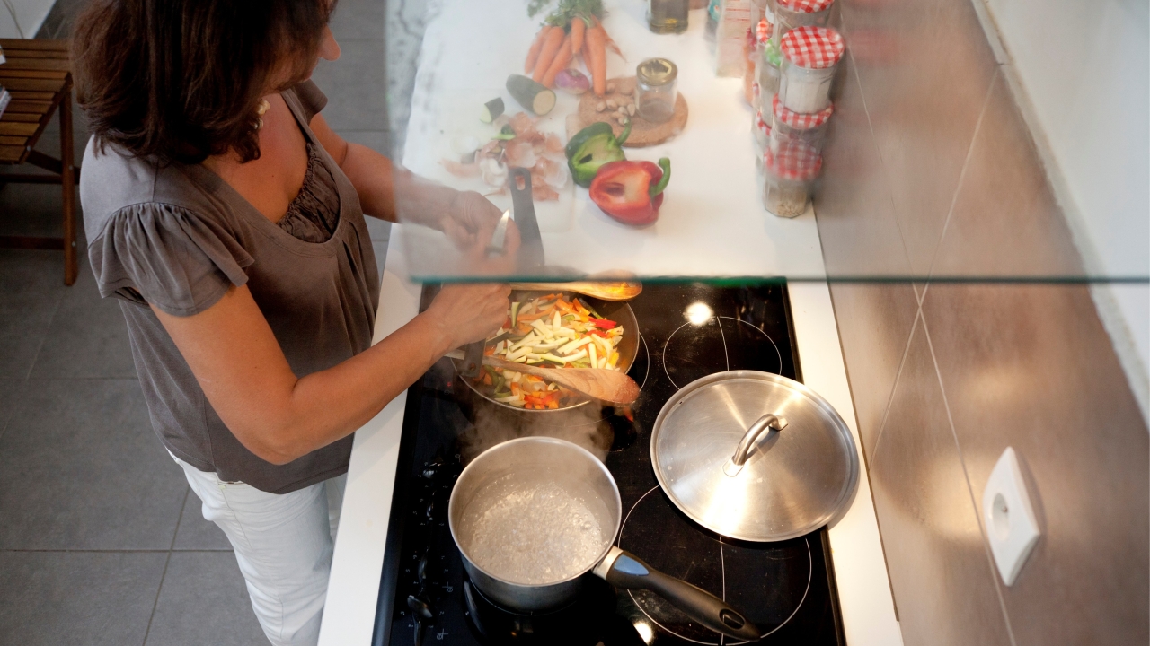 Photographie vue de dessus d'une plaque de cuisson où une femme prépare son repas