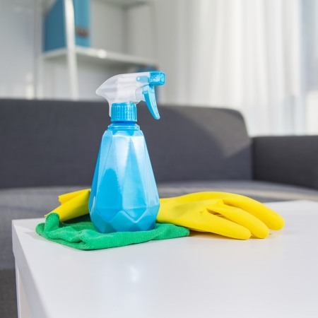 Un produit d'entretien en spray sur une table basse avec un gant et un chiffon