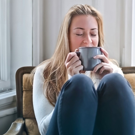 Une femme se réchauffe en buvant une boisson chaude en hiver sur un fauteuil