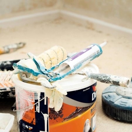 Photographie d'un chantier avec un pot de peinture, un rouleau et un pistolet à joint