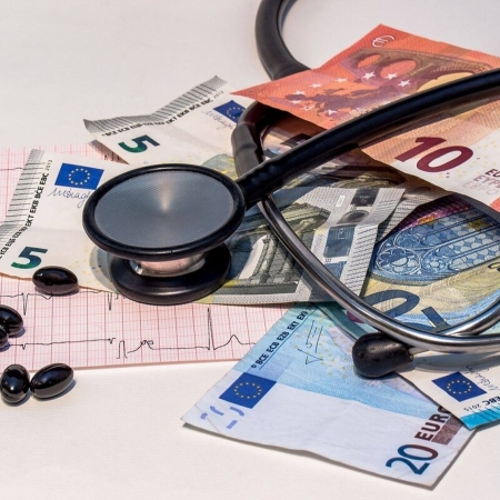 Photographie d'un stetoscope, de pilules, d'un électrocardiogramme et de billets en euros pour illustrer le coût de la qualité de l'air intérieur