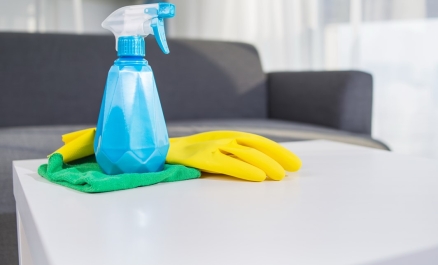 Un produit d'entretien en spray sur une table basse avec un gant et un chiffon