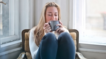 Une femme se réchauffe en buvant une boisson chaude en hiver sur un fauteuil