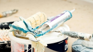 Photographie d'un chantier avec un pot de peinture, un rouleau et un pistolet à joint