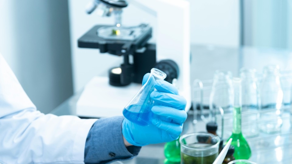 Un microscope et des instruments de chimie manipulés par une personne dans un laboratoire