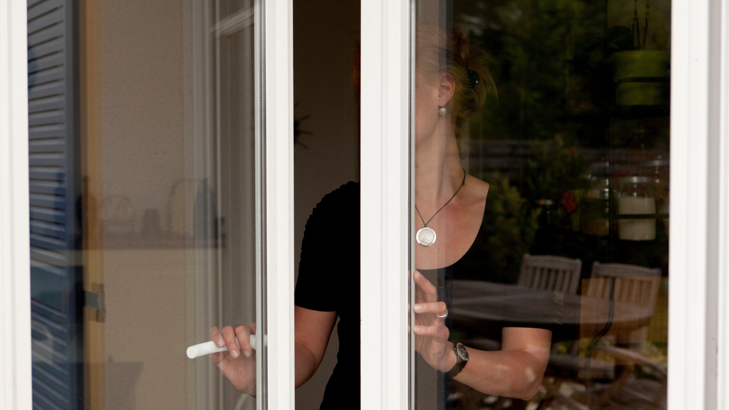 Photographie d'une femme qui ouvre les fenêtres de son logement